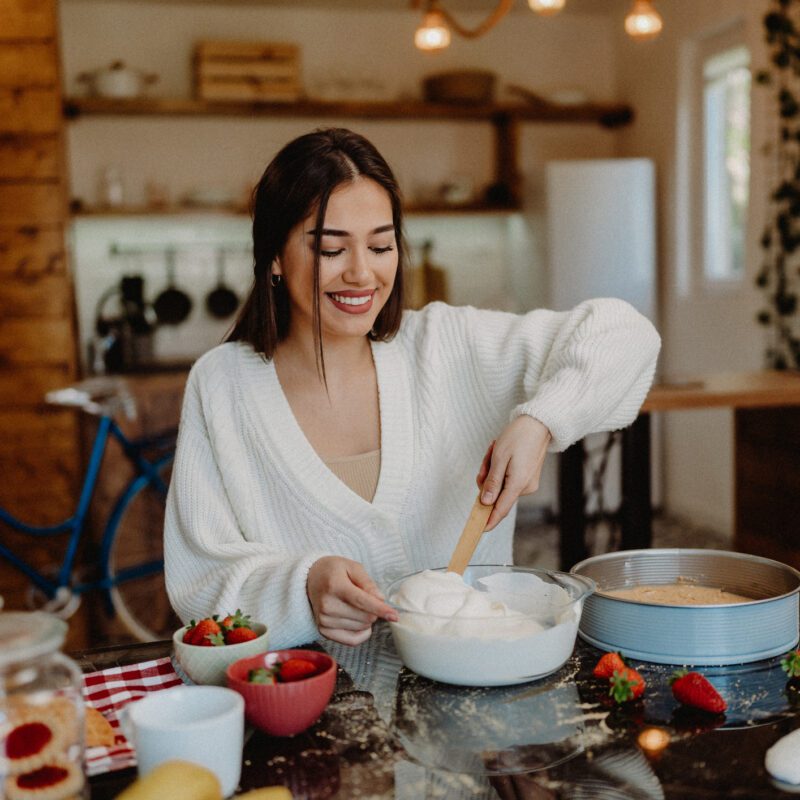 Young woman preparing cheesecake at home