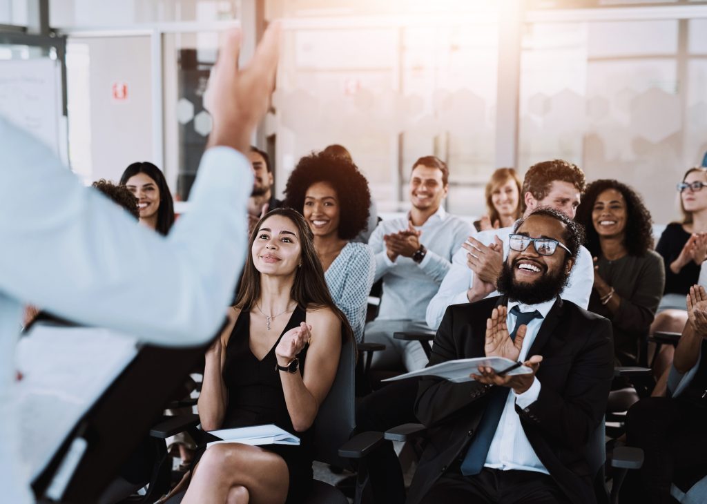 People, speaker and applause at workshop in office for training, support for company conference or event. Celebrate, inclusion presentation and corporate award for team building with staff at seminar