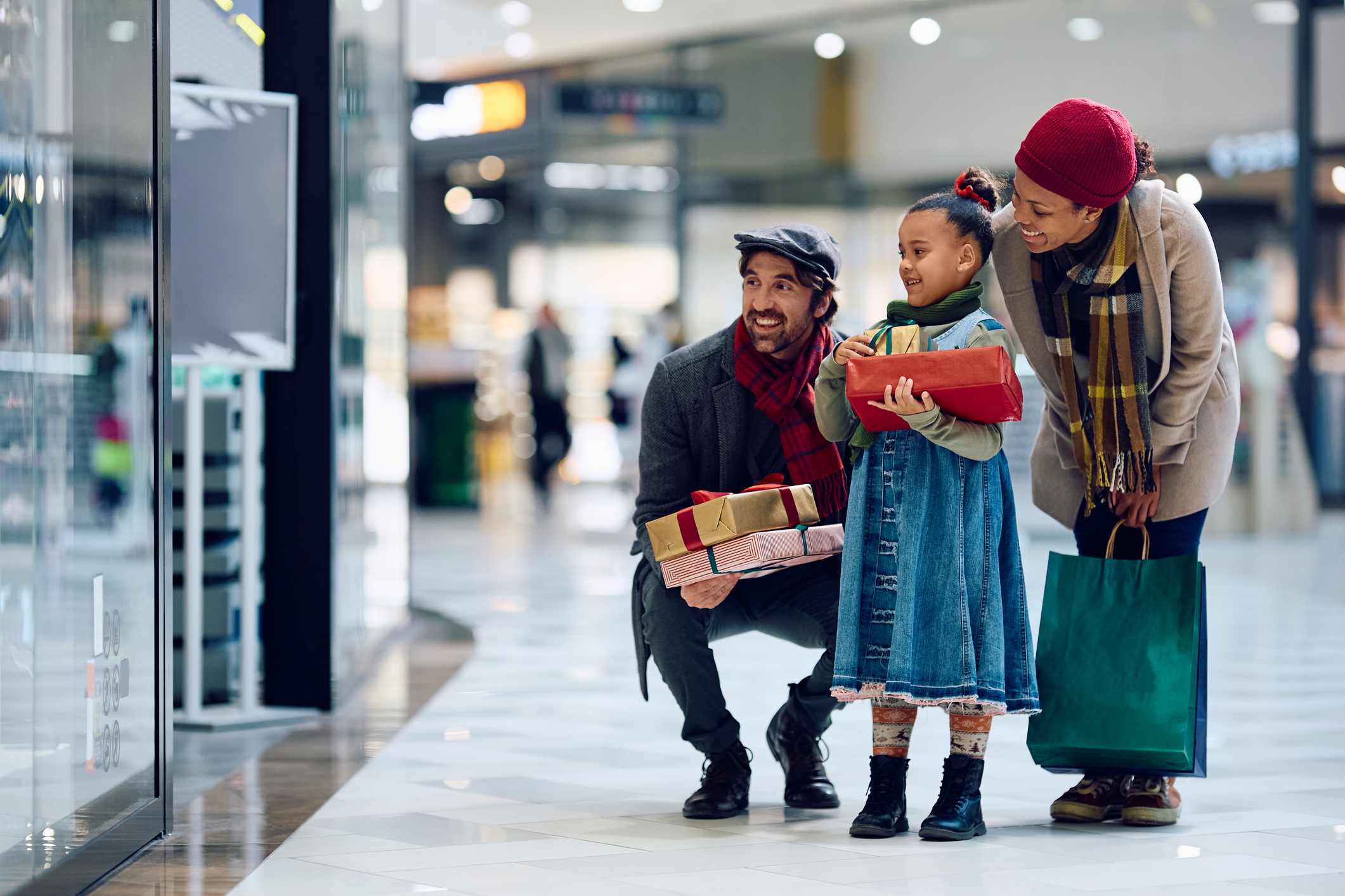 Happy family looking at store windows while buying Christmas present at shopping mall.