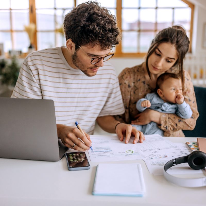 Image: Young couple with baby budgeting at table with laptop.