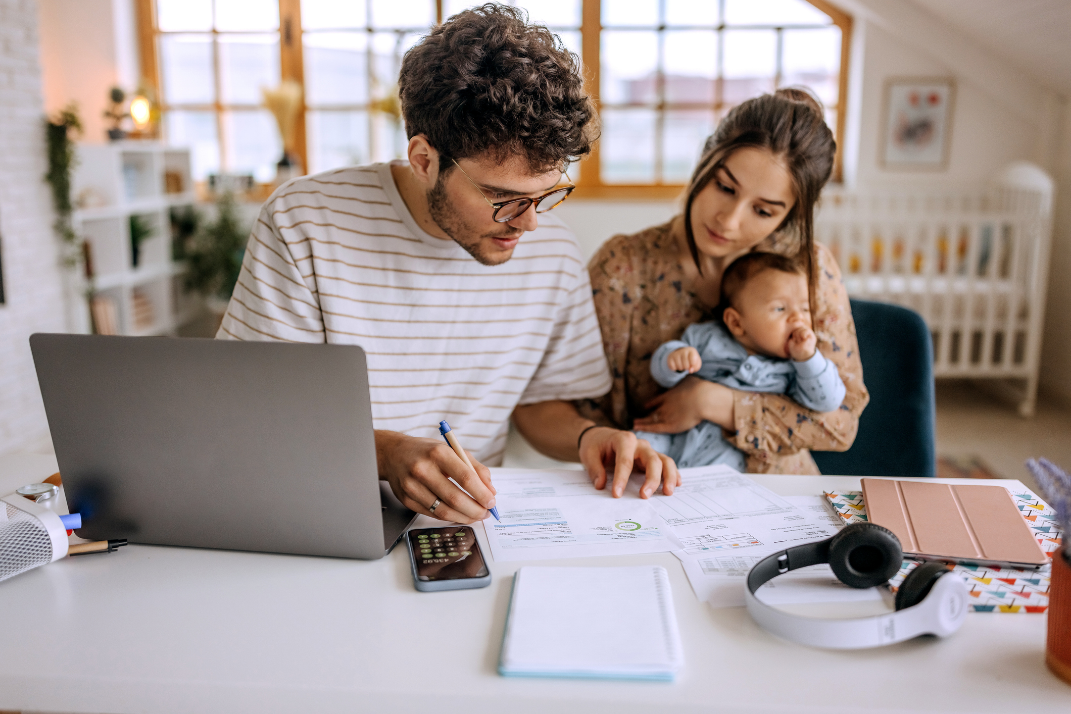 Image: Young couple with baby budgeting at table with laptop.