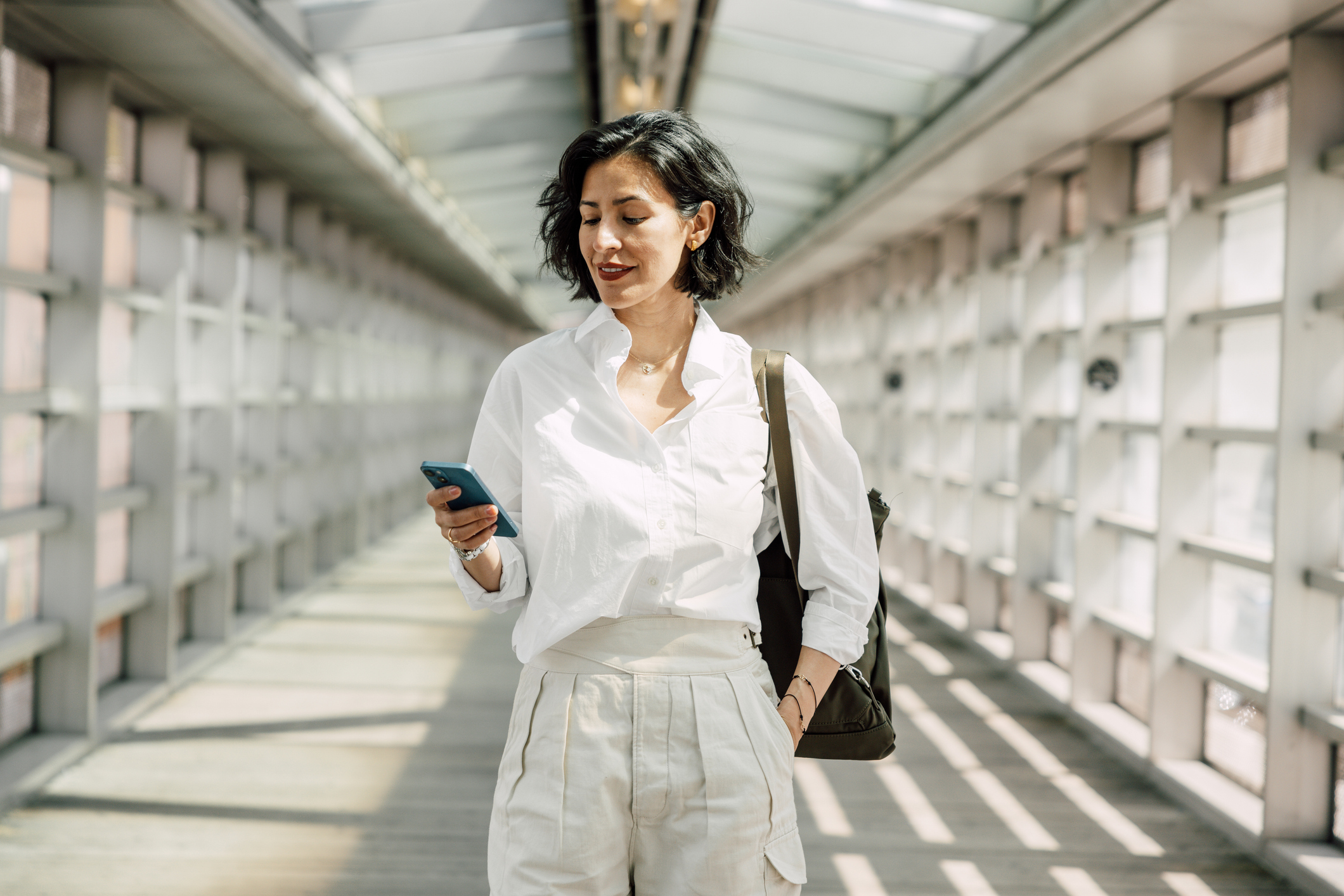 Image: Woman in business dress walking and using phone.