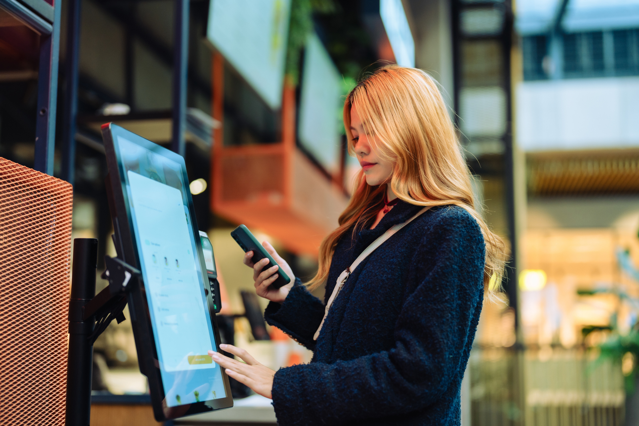 Woman at cashier counter uses smartphone for payment..